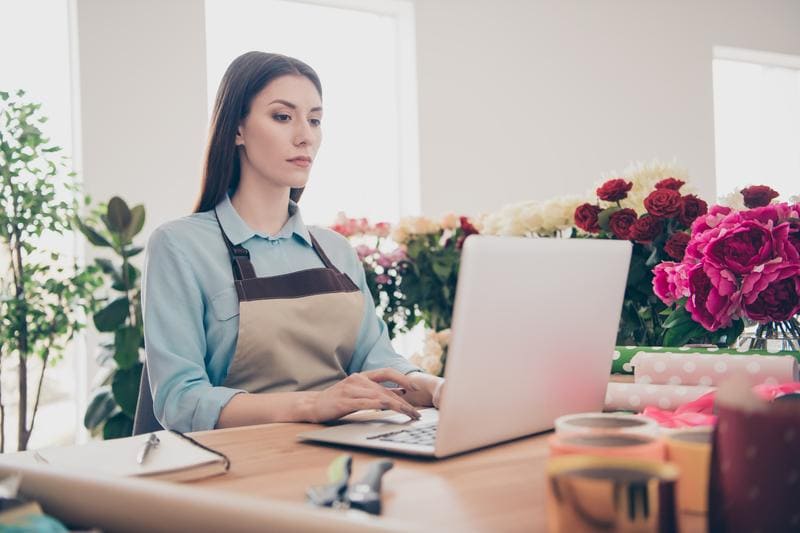 Woman working at computer surrounded by flowers